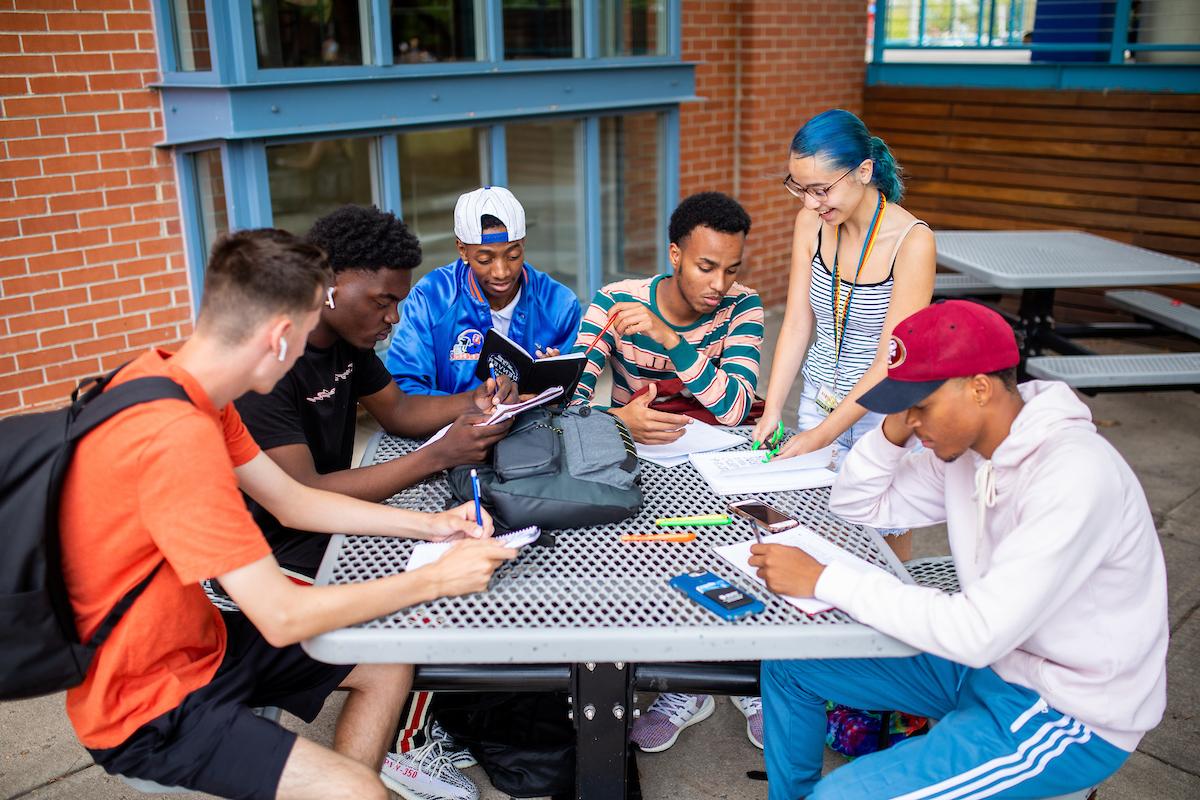 Six students studying with their notebooks at table outside of the Tivoli Student Union