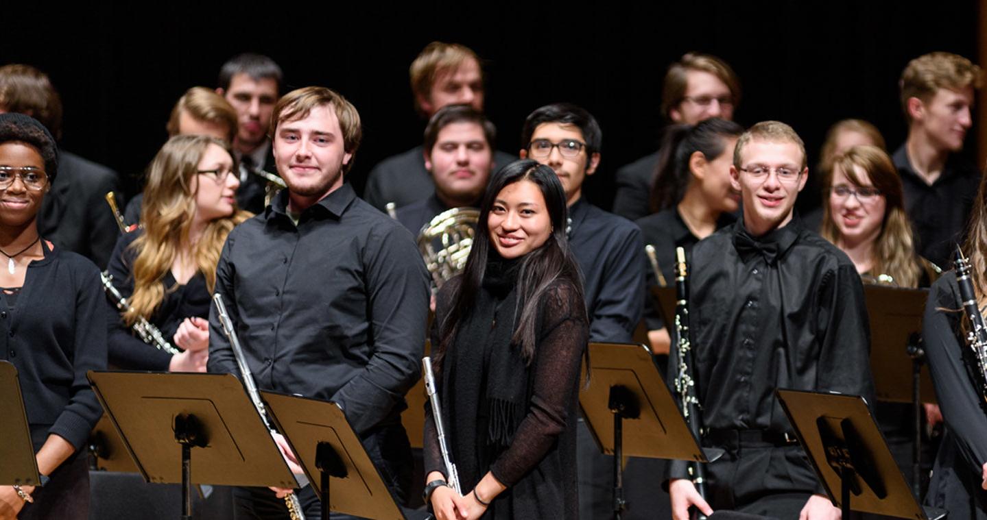 Flute section of a symphonic band standing and smiling after a performance