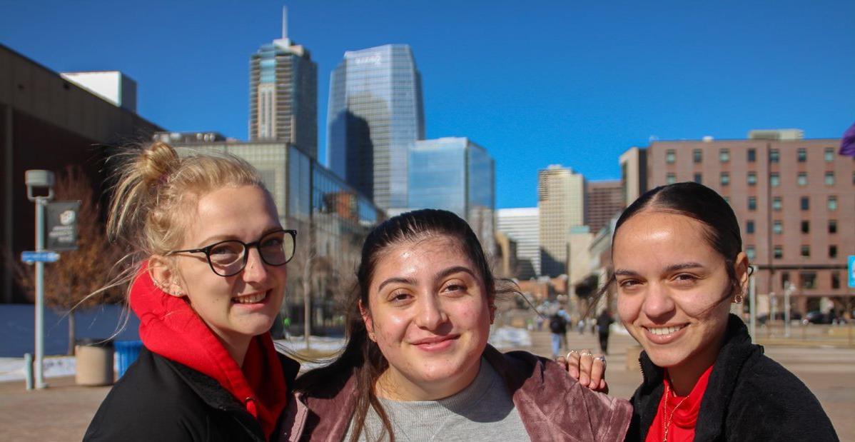 Three students in front of Denver skyline
