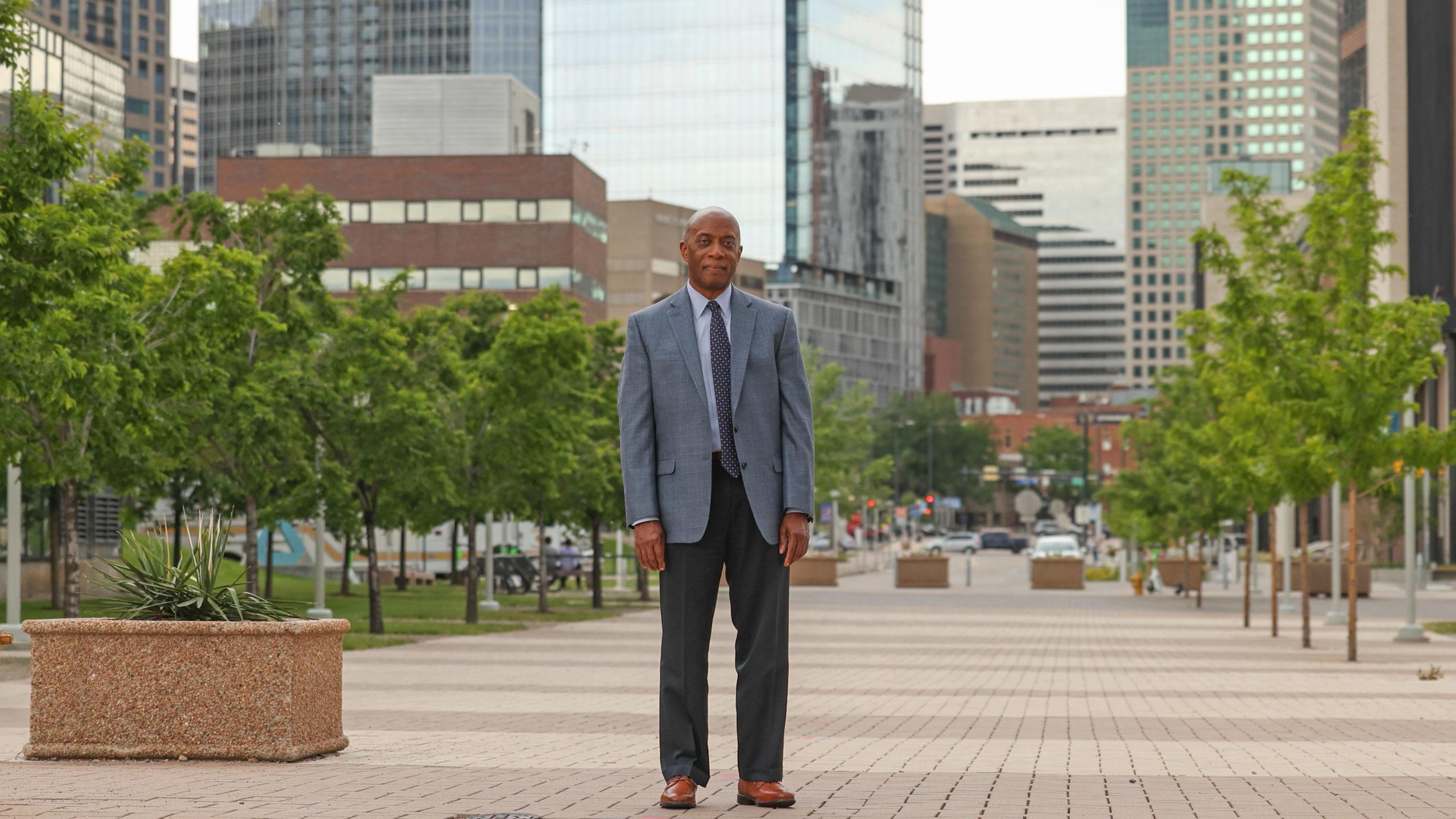 Russell Noles standing near the Auraria Events Center with downtown Denver in the background