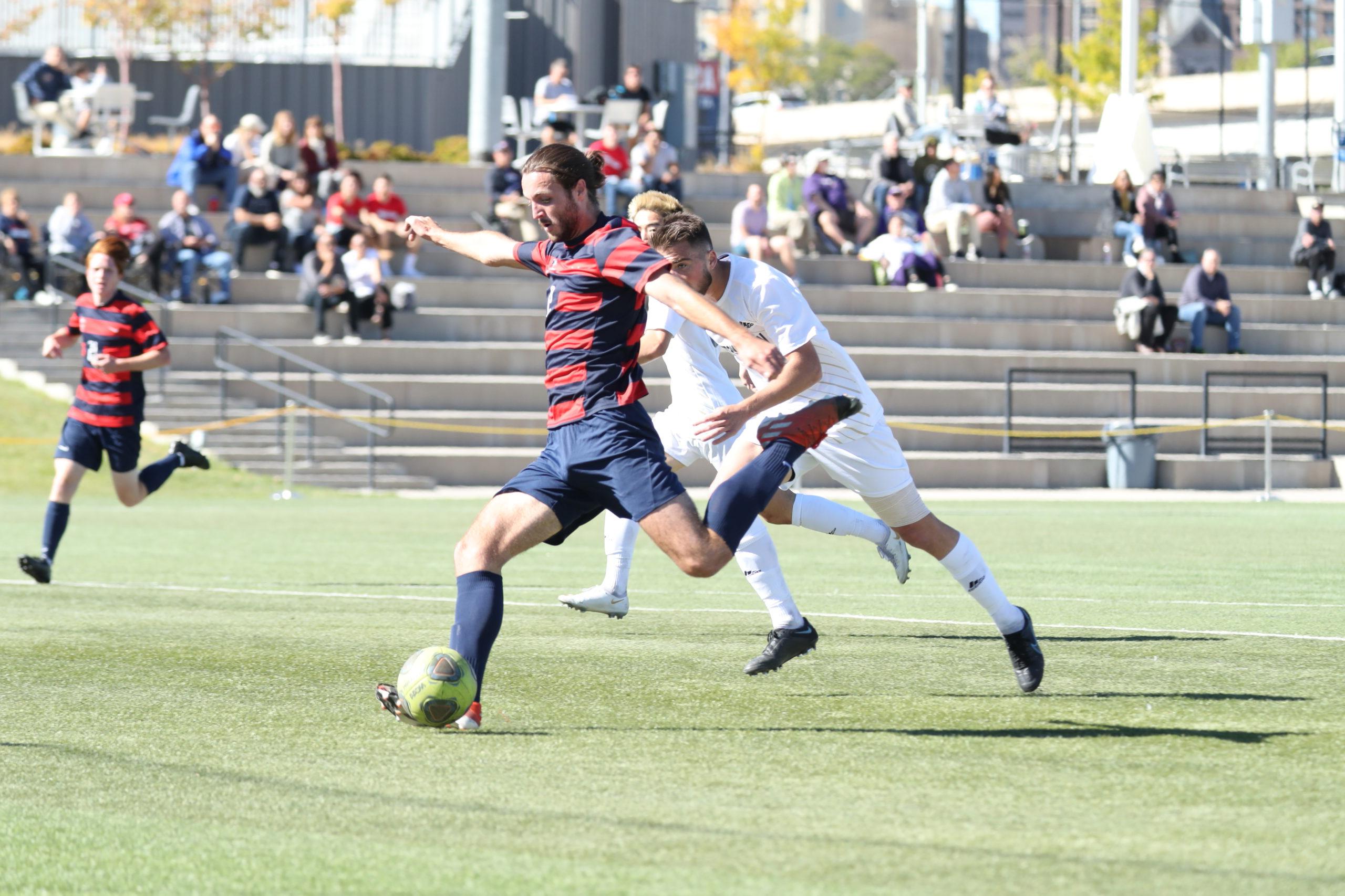 Men's soccer player Aidan Bates sets up for a shot during a game in 2021 with the Roadrunners crowd in the background.