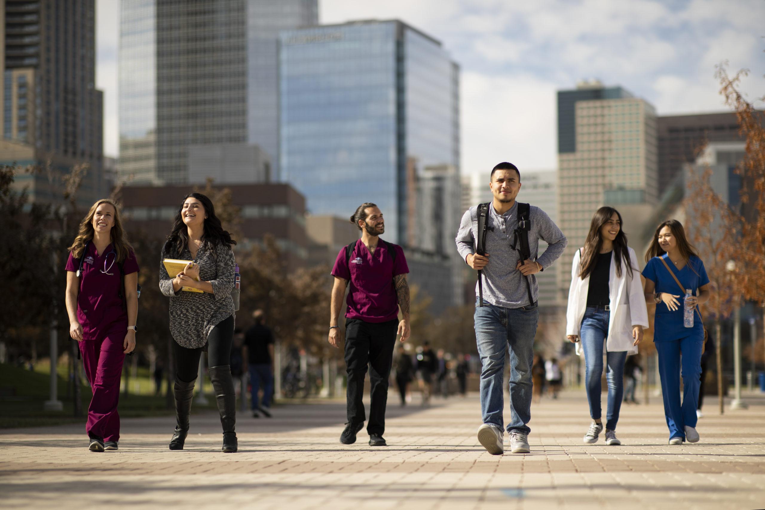 Group of students walking through campus with downtown Denver in the background.