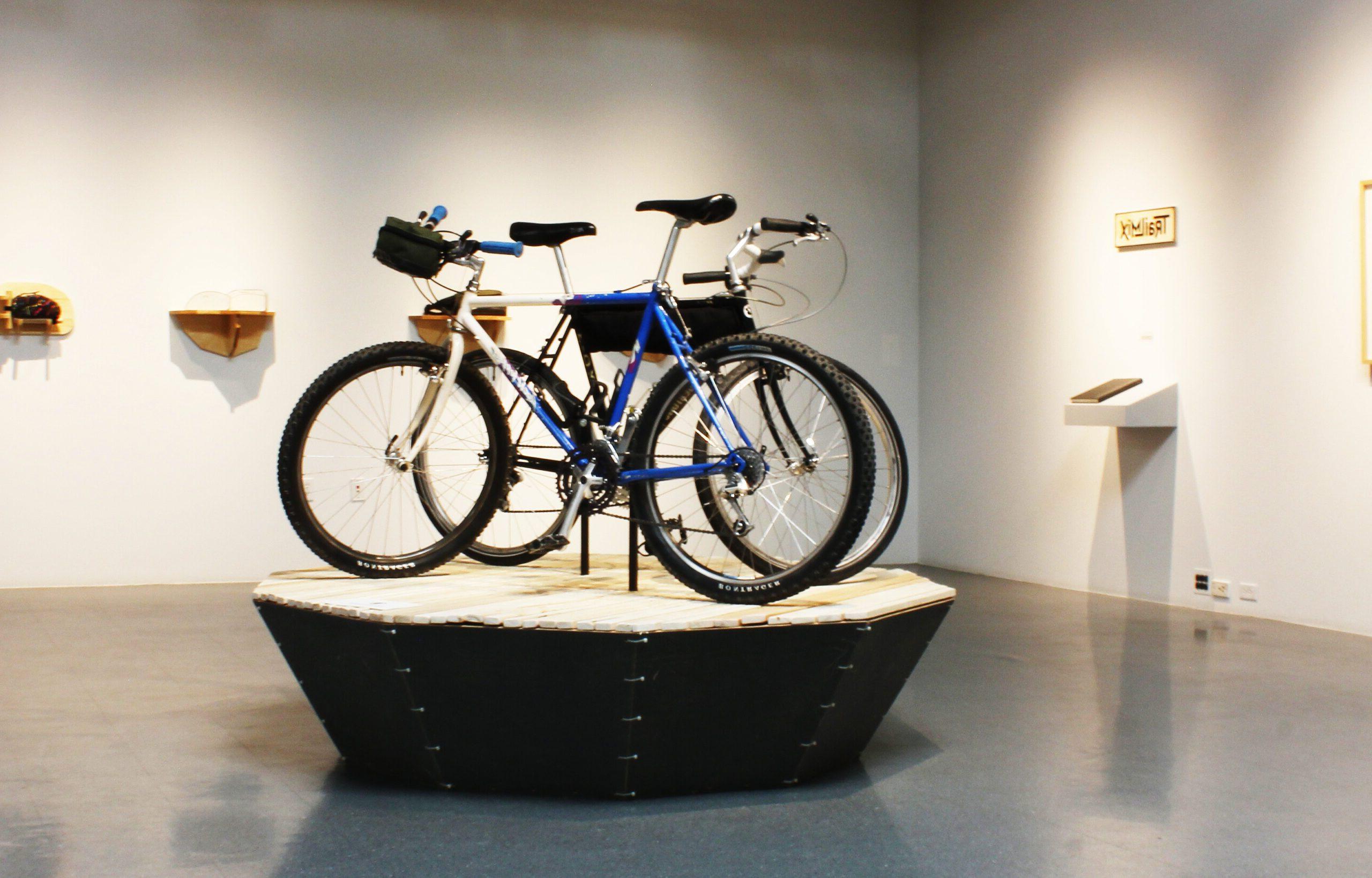 Gallery space with tall ceilings two bicycles outfitted with gear.